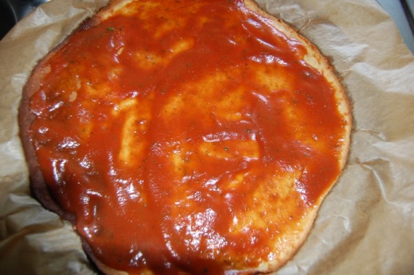 weizenloser-pizzateig-mit-tomatensauce-bestreichen